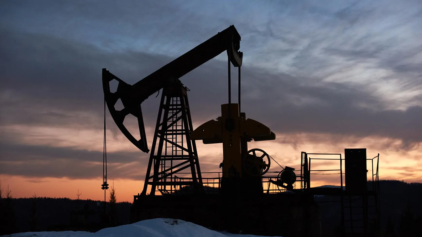 Oil pump jack silhouetted against a sunset sky
